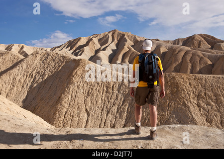 A hiker looks out over the Black Mountains during an evening hike of Golden Canyon in Death Valley National Park, California. Stock Photo