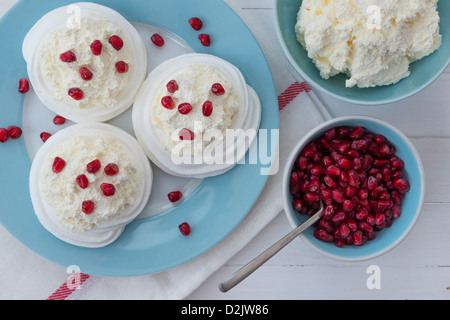 Meringue nests with fresh whipped cream and pomegranate seeds. Stock Photo