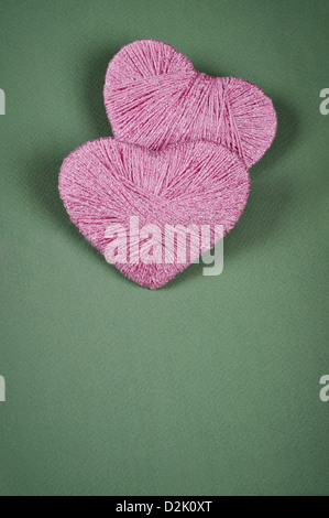 Two pink clews in shape of heart on green background Stock Photo