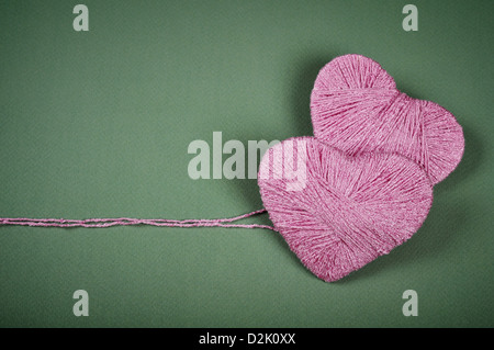 Two pink clews in shape of heart on green background Stock Photo