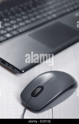 Laptop with computer mouse on the table closeup Stock Photo