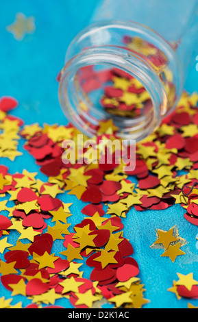 Shiny red love hearts and gold stars coming out of a glass jar on blue star shawl Stock Photo