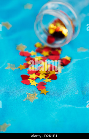 Shiny red love hearts and gold stars coming out of a glass jar on blue star shawl Stock Photo