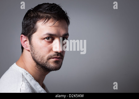 Young handsome man with serious expression on dark background Stock Photo