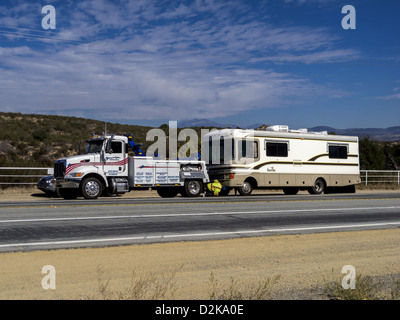 A broken down motorhome being attached to a tow truck on a  highway Stock Photo