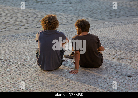 Two young men sitting on the cobbles in Prague Old Town Square Stock Photo