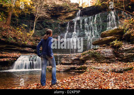 A woman stands in front of a large waterfall Stock Photo