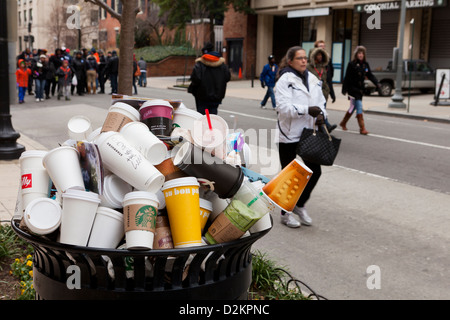 Discarded coffee cups overflowing from public trash bin Stock Photo