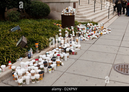 Discarded coffee cups overflowing from trash bin on public street Stock Photo