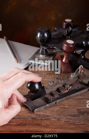 Hand tapping morse code on an antique telegraph machine Stock Photo