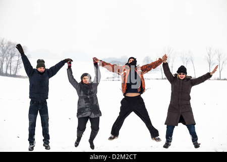 Group of young happy people jumping in snow and enjoying winter. Stock Photo
