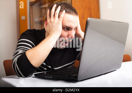 Young shocked man using looking at laptop. Stock Photo