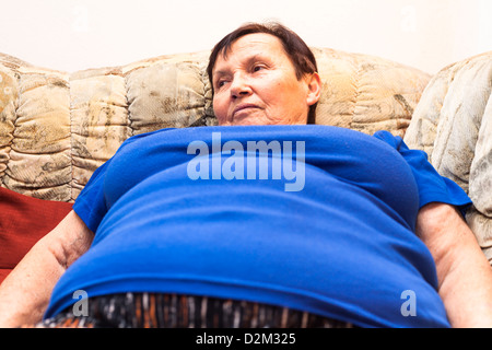 Close up of obese senior woman lying on sofa. Stock Photo