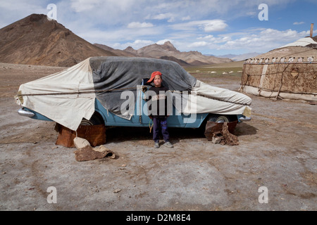 A boy in front of a covered car in a yurt camp in eastern Tajikistan. Stock Photo