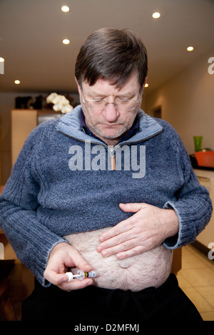 A man self injecting with Clexane to prevent post op DVT ( deep vein thrombosis); UK Stock Photo