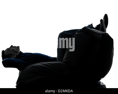one  man sitting full length in silhouette studio on white background Stock Photo