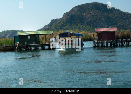 Tourist boat with blue awning passes through the fish gates on way to beach on Dalyan River Stock Photo