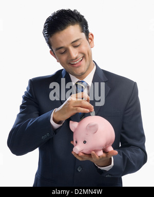 Businessman putting a coin into a piggy bank Stock Photo