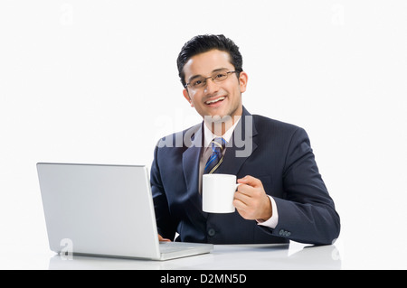 Businessman drinking coffee while working on a laptop Stock Photo