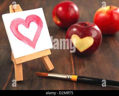 Fresh red apple with a heart shaped cut-out and painted heart Stock Photo