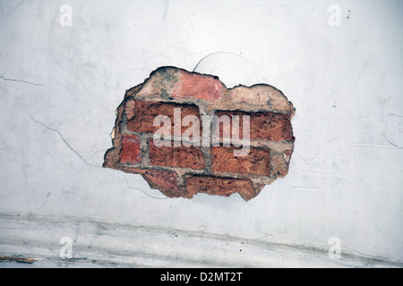 It's a photo of a close up of a detail of a destroyed wall. We can see a hole in the bricks. It's ruined and old Stock Photo