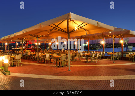 Illuminated outdoor restaurant on marina promenade on Mediterranean sea at evening in Ashqelon, Israel. Stock Photo