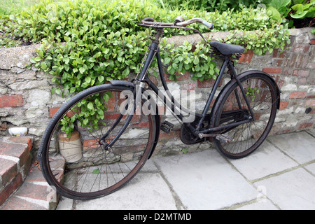 Rusty antique Ladies Loop Frame (Sit up and Beg) Bicycle, Bike in English country cottage garden. Stock Photo