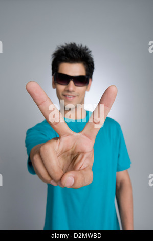 Close-up of a man showing victory sign Stock Photo