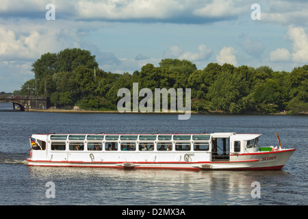 One of the tour boats that ply the popular Alster Lake, with the Lombardsbruecke beyond; Hamburg, Germany Stock Photo