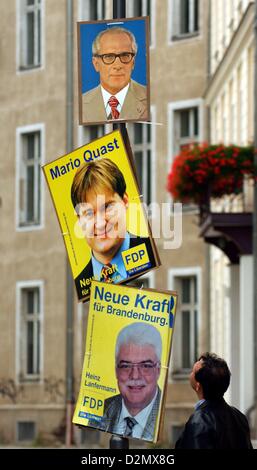 A man stands in front of a lamp pole on which the portrait of the former Chairman of the State Council of the GDR Erich Honecker was put up above the posters of the election campaings for the Brandenburg elections in 2004. Strangers put up the images in different places around the city as a joke. Photo: Patrick Pleul Stock Photo