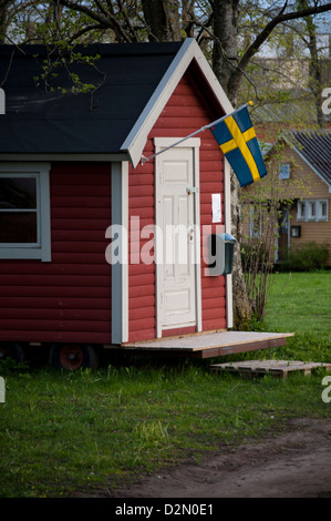 Small red wooden house with white trimmings and a Swedish flag in historic town of Vadstena Sweden Stock Photo