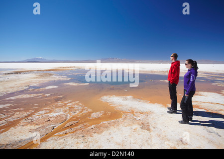 Couple standing next to geyser on Salar de Uyuni (Salt Flats of Uyuni), Potosi Department, Bolivia, South America Stock Photo