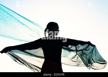 Indian girl with veils turning in the wind towards the sun. Silhouette. India Stock Photo
