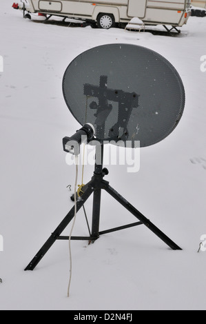 A satellite dish supplying  signals to caravan in an all season caravan park photographed during january's snow fall Stock Photo
