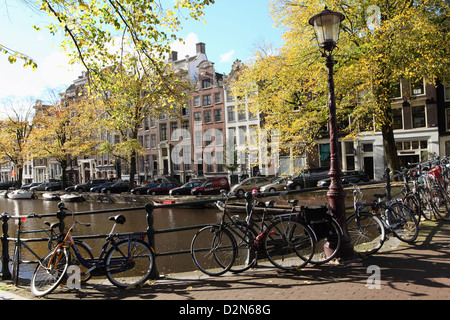 Bicycles chained to railings by a canal on a sunny day in Amsterdam, The Netherlands, Europe Stock Photo