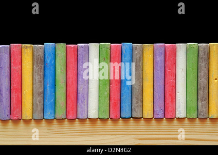 Color chalks arranged in line on blackboard Stock Photo