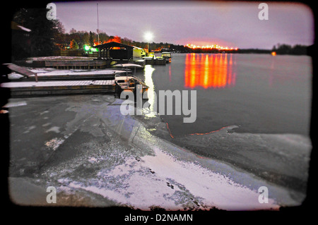 1000 Islands Bridge lit in orange from the shores of Ivy Lea in the winter with ice on the St Laurence River Stock Photo