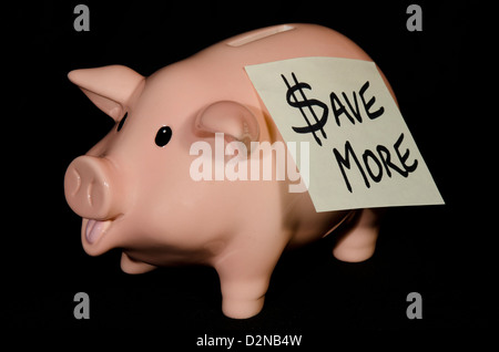 This empty little piggy bank has a note on his side to remind him to save more money, rather than spend it. Stock Photo