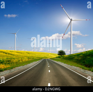 Rural road across the field to wind power Stock Photo