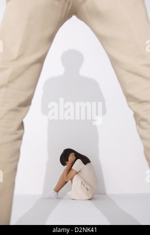 Girl in a white dress sitting scared on the floor Stock Photo