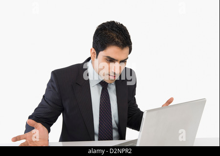 Businessman looking confused while using a laptop Stock Photo