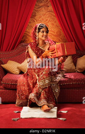 Bride in traditional wedding dress and holding a gift Stock Photo