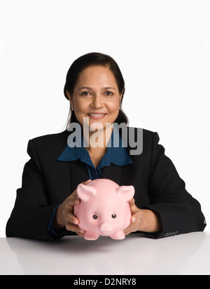 Portrait of a businesswoman holding a piggy bank and smiling Stock Photo