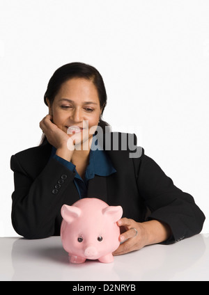 Businesswoman leaning on her desk with a piggy bank Stock Photo - Alamy