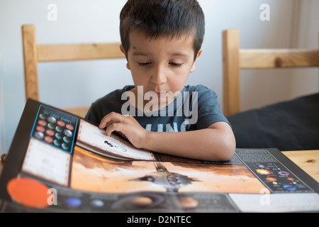 5 year old boy reads a book about planets Stock Photo
