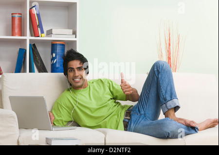 Man showing thumbs up sign while using a laptop Stock Photo