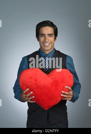 Portrait of a businessman offering a heart shaped cushion and smiling Stock Photo