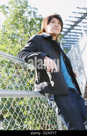 Young man leaning on a fence Stock Photo