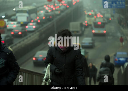 A woman wears a mask past heavy traffic in thick haze in Beijing, China. 30-Jan-2013 Stock Photo
