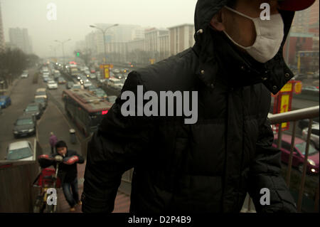 A man wearing a mask past heavy traffic in thick haze in Beijing,  China. 30-Jan-2013 Stock Photo